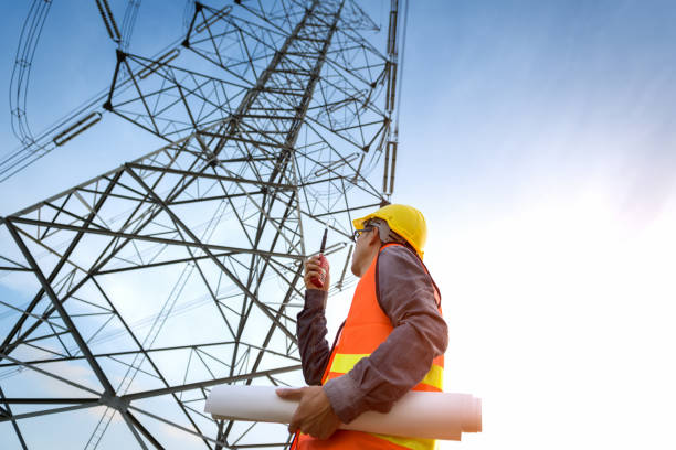 construction worker checking location site near to high voltage tower.